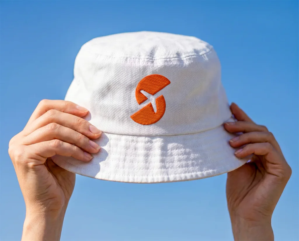 Spoko Travel: sygnet marki wyhaftowany na białym bucket hacie