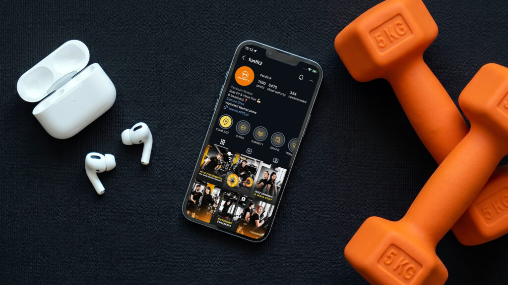 Funfit II: profil klubu na Instagramie w telefonie obok hantli, social media PIONA Studio